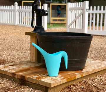 watering can and bucket next to a water spigot