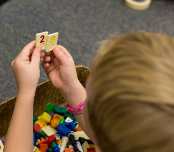 boy comparing two number tiles