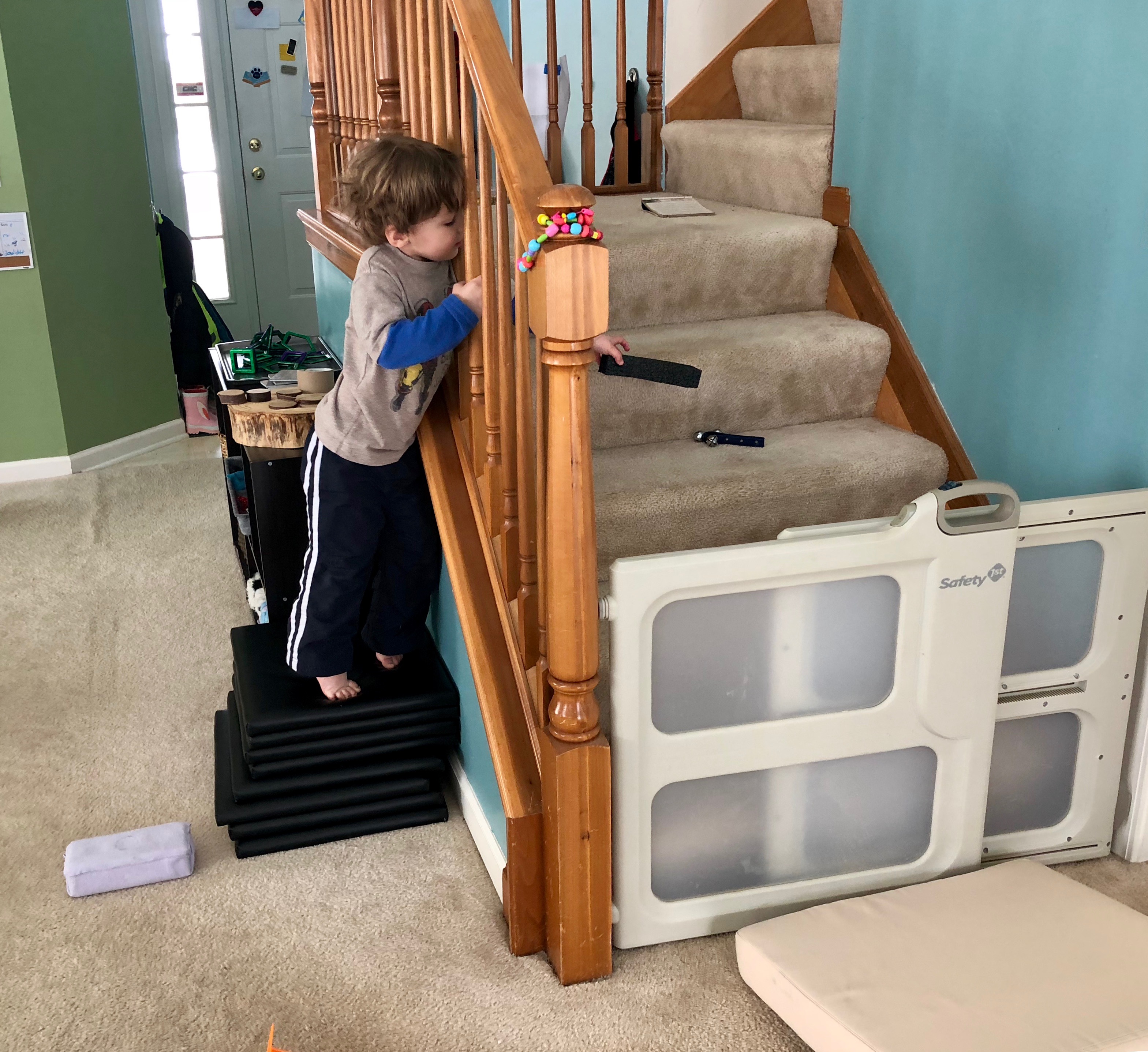 boy reaching for bell on the stairs with a foam block