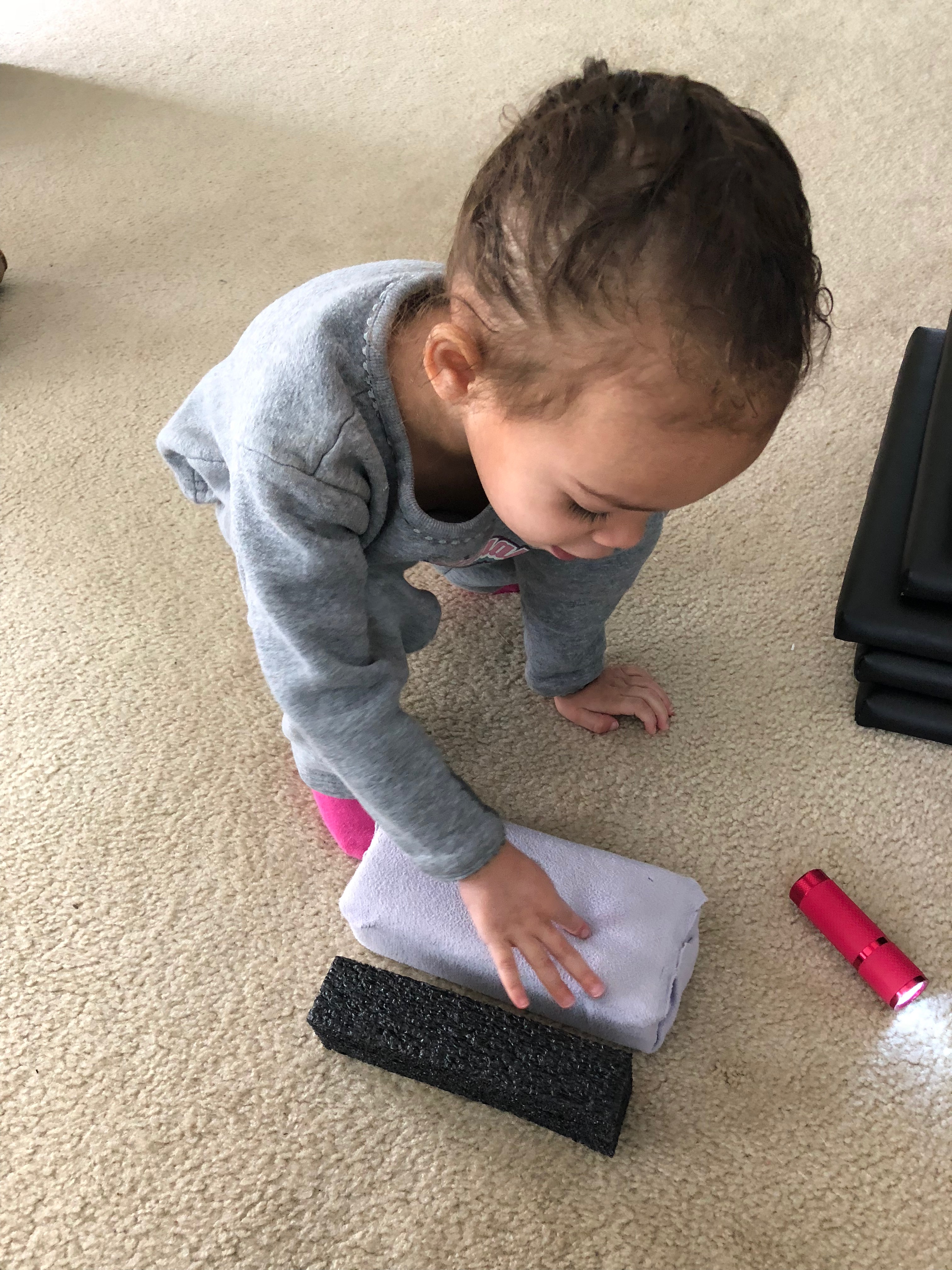 girl comparing the length of a brick to a foam block