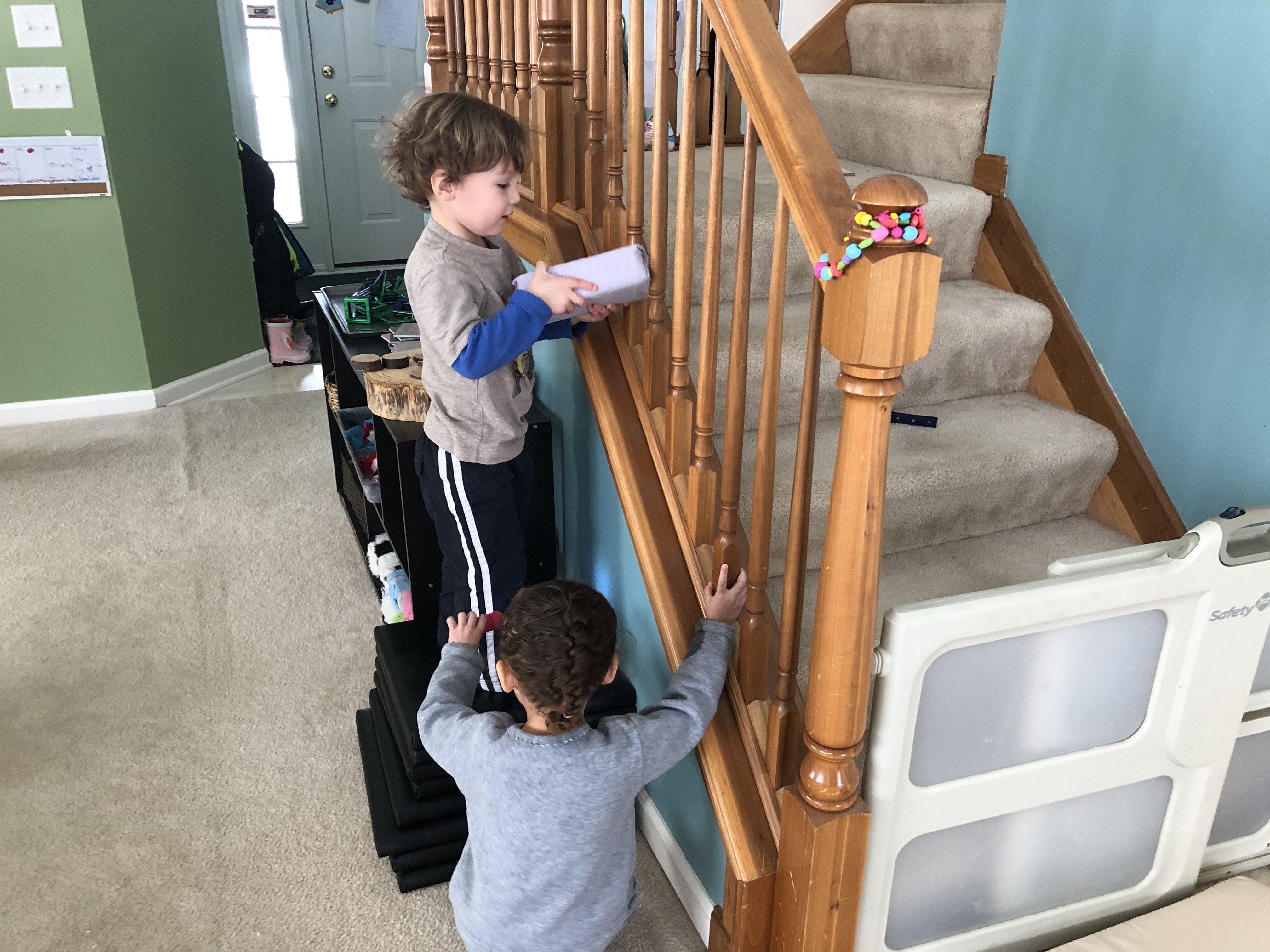 boy trying to fit brick between stair spokes