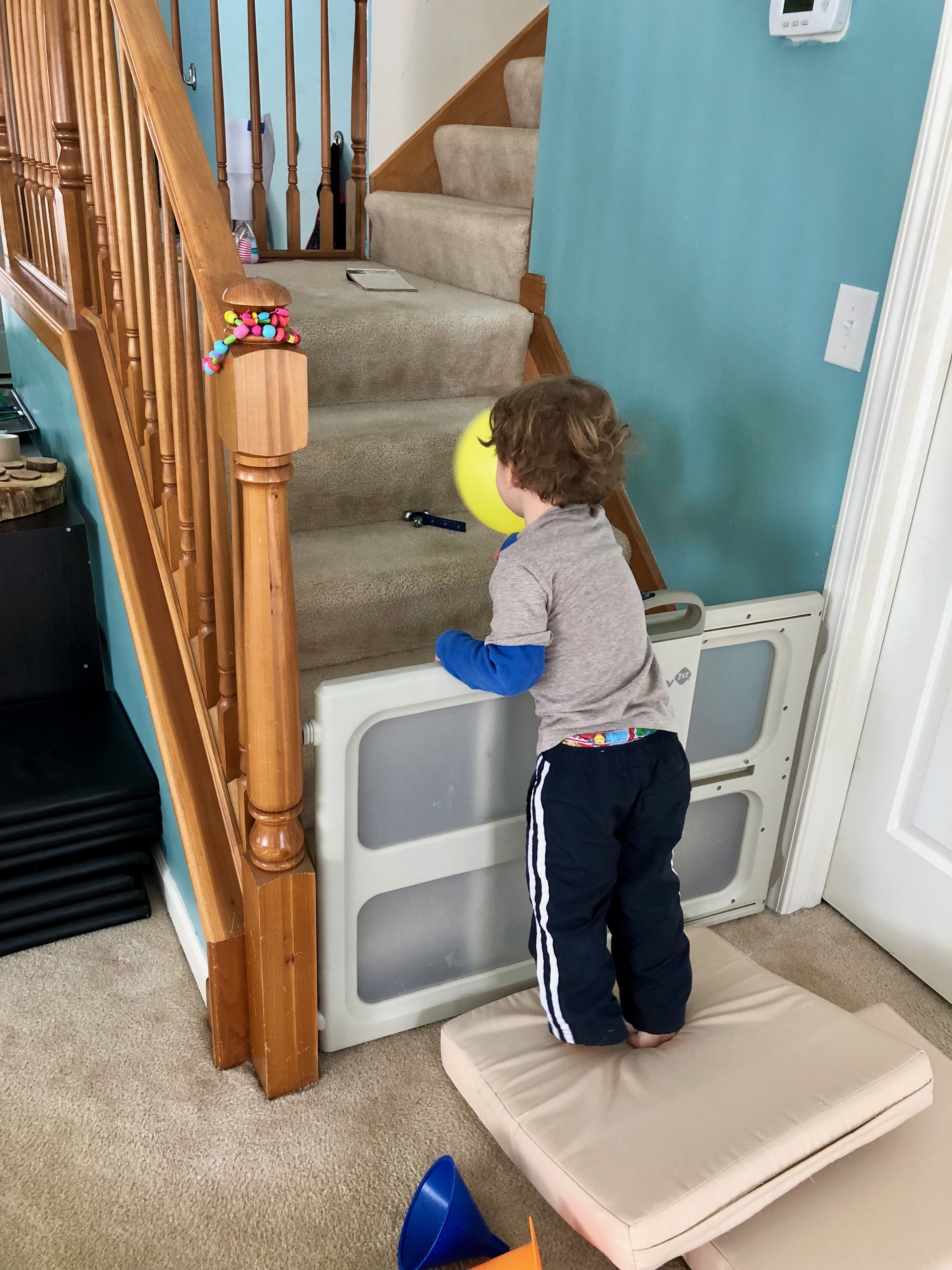 boy reaching for bell on the stairs with a balloon