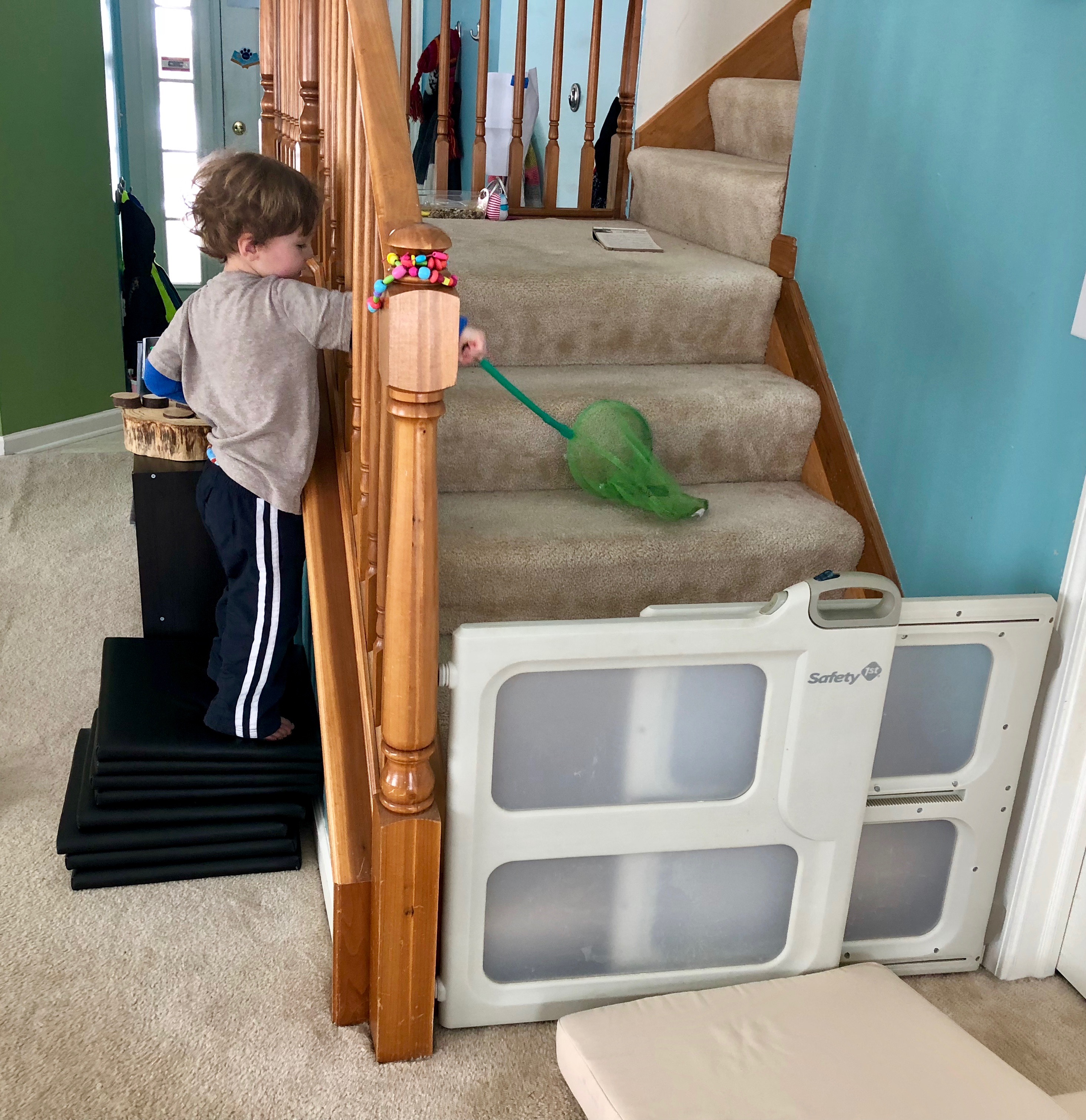 boy trying to grab bell on the stairs with a net