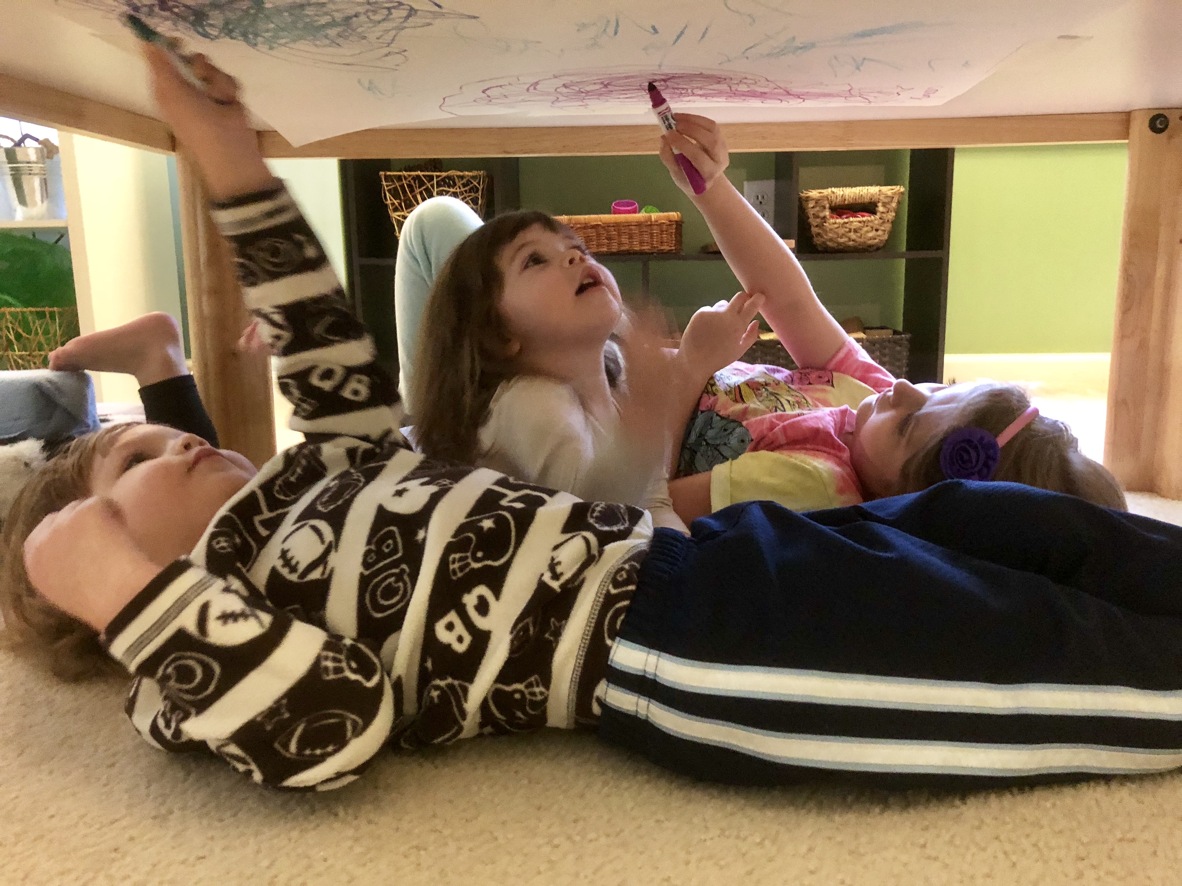 children coloring on the underside of a table