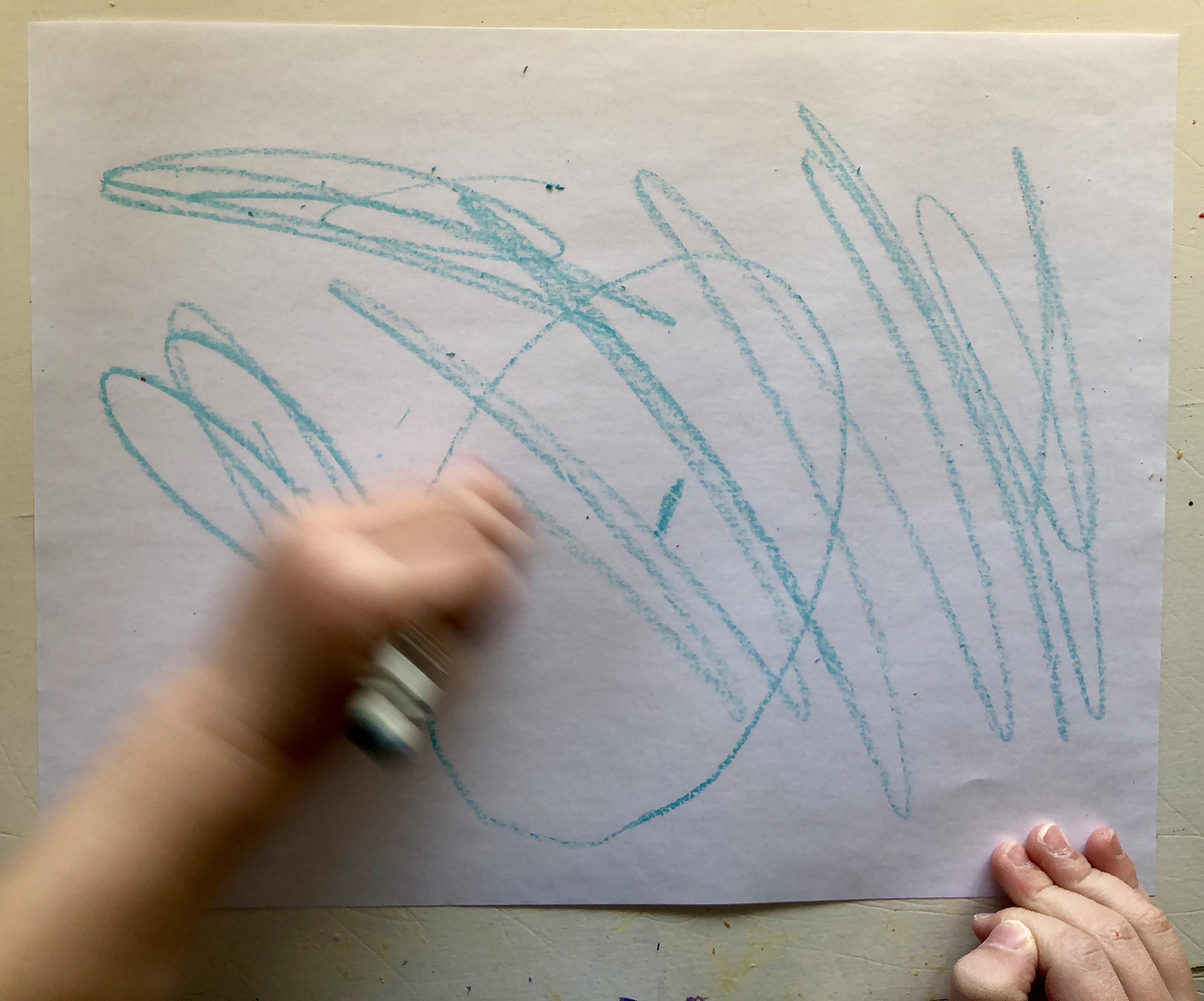 child's hand scribbling with a crayon