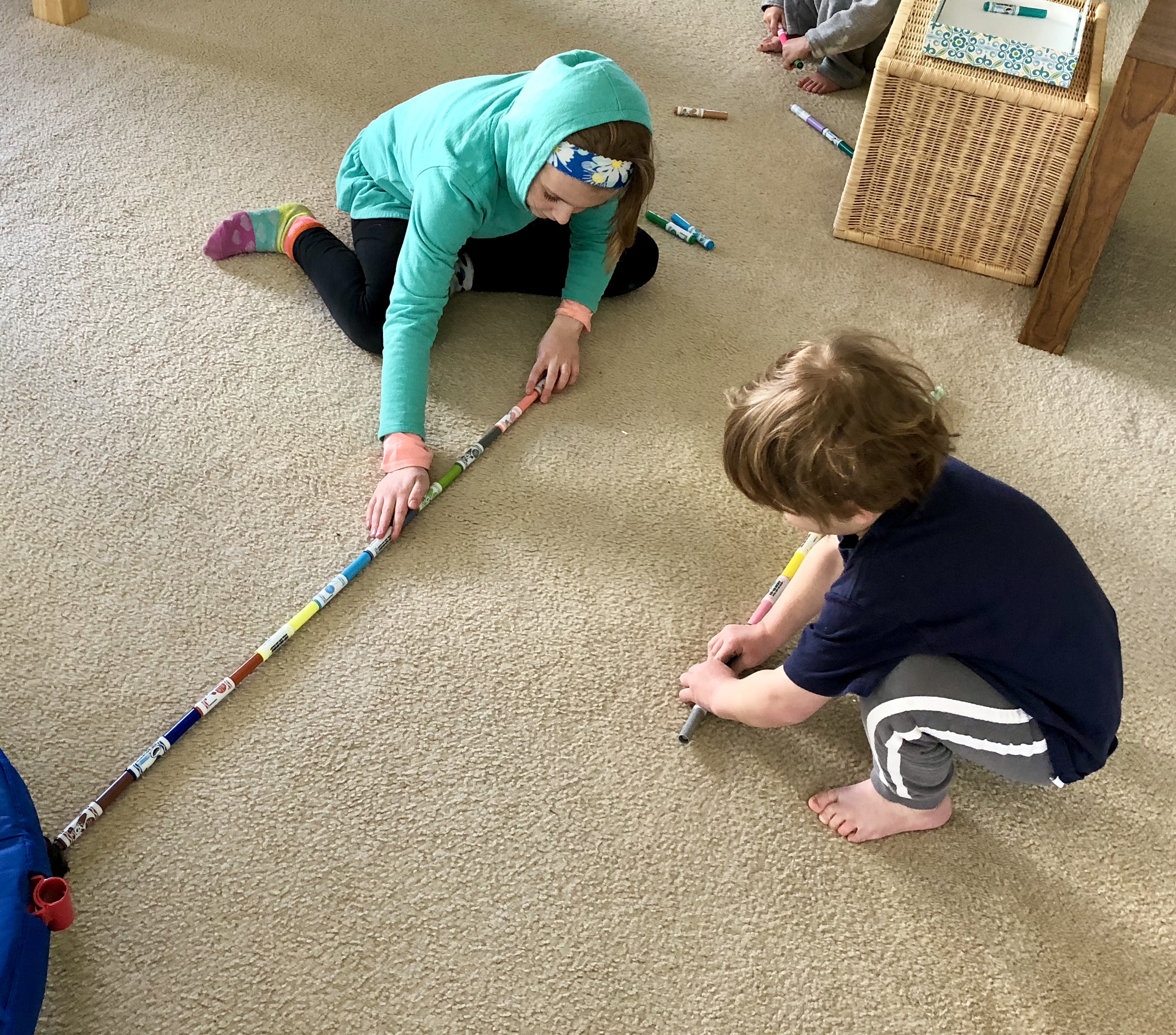 2 children building markers across the floor to reach a basket