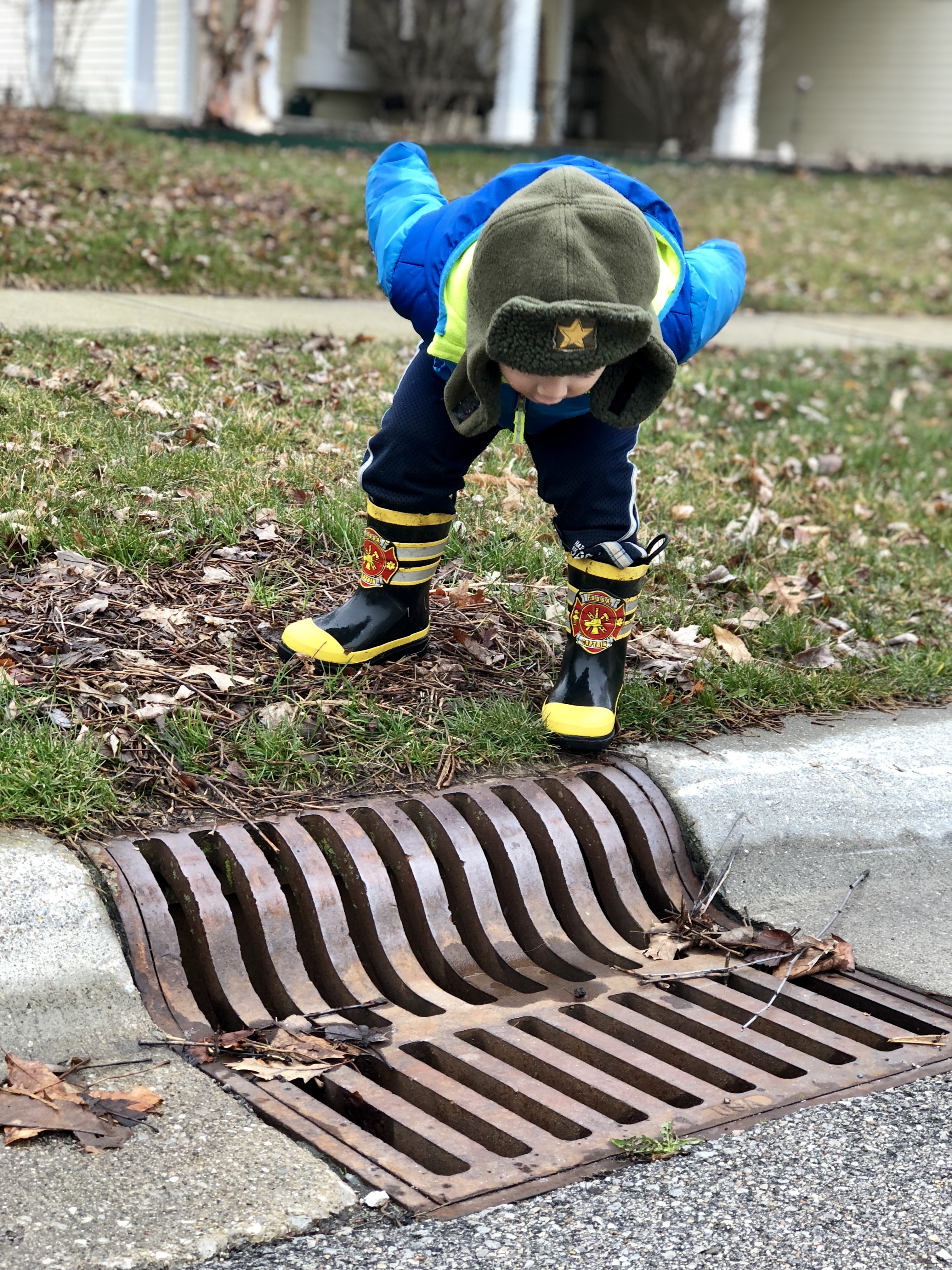 boy leaning over a drain and calling into it