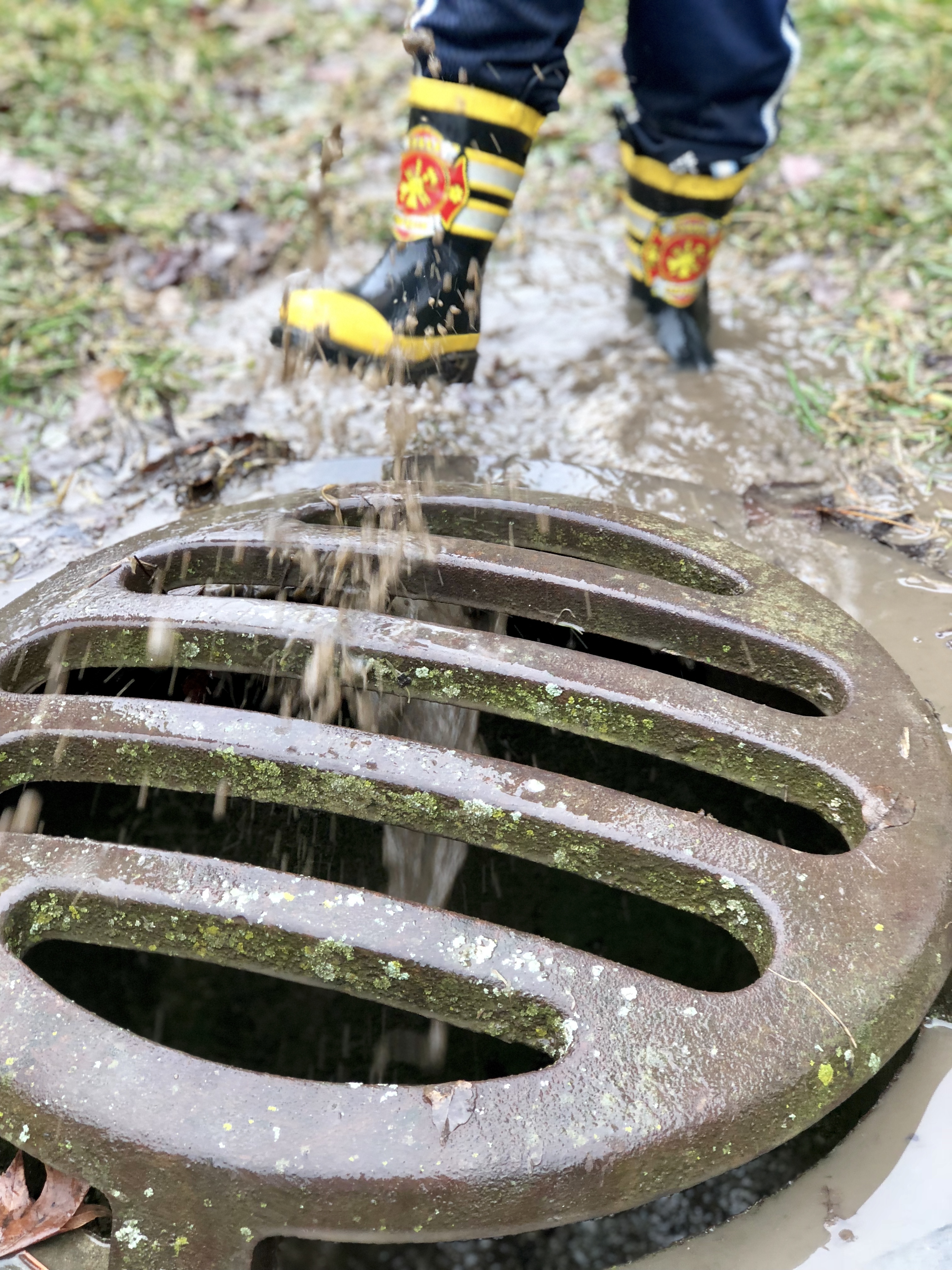 boy kicking water into a drain