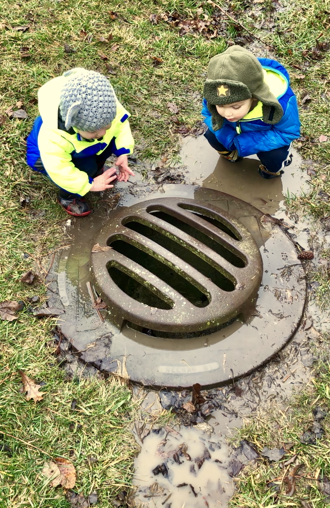 2 boys leaning over a drain