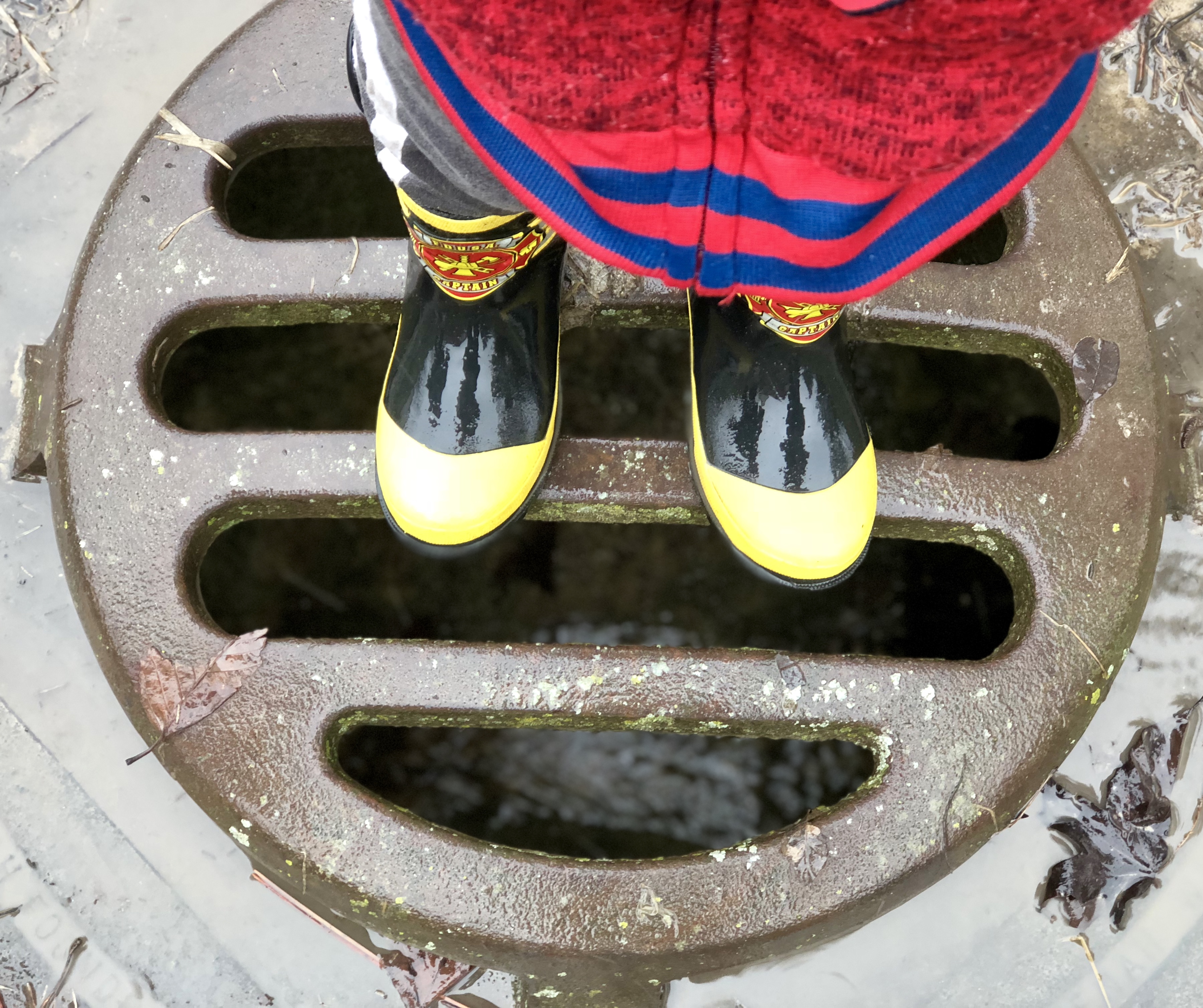 child's feet standing on a drain