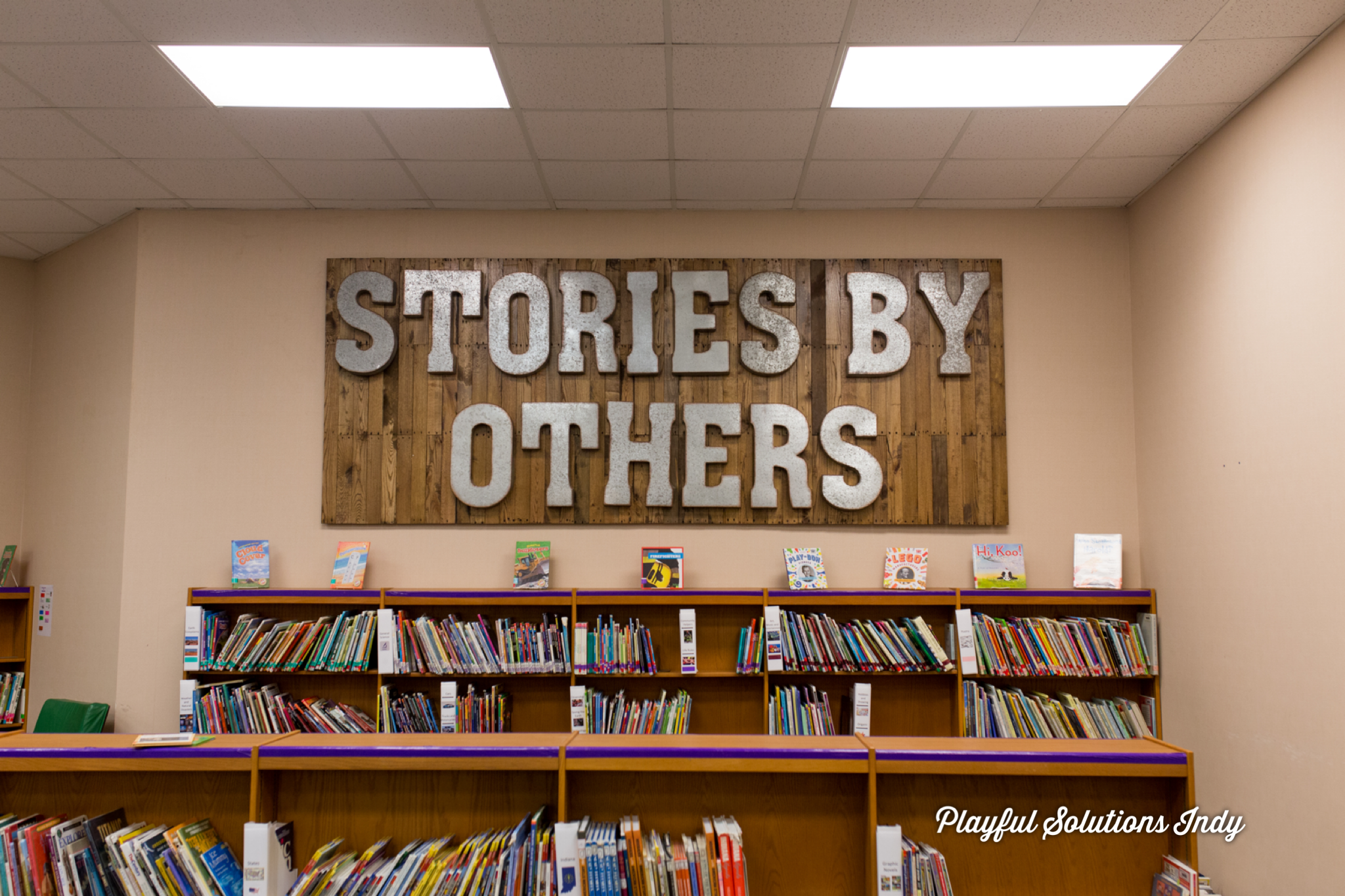 Large bespoke wooden sign with metal letters spelling out stories by others