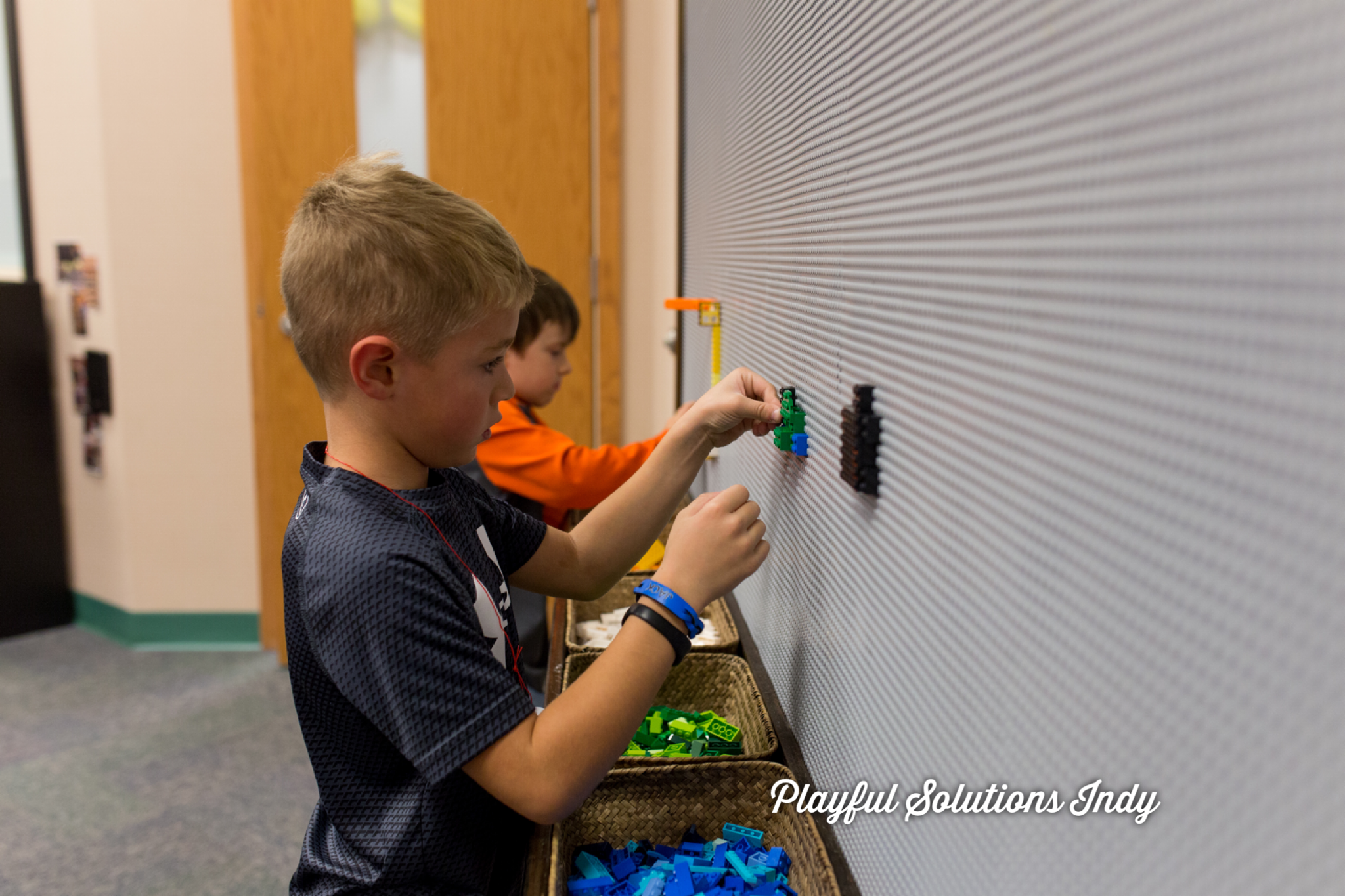 Boys building on a Lego wall