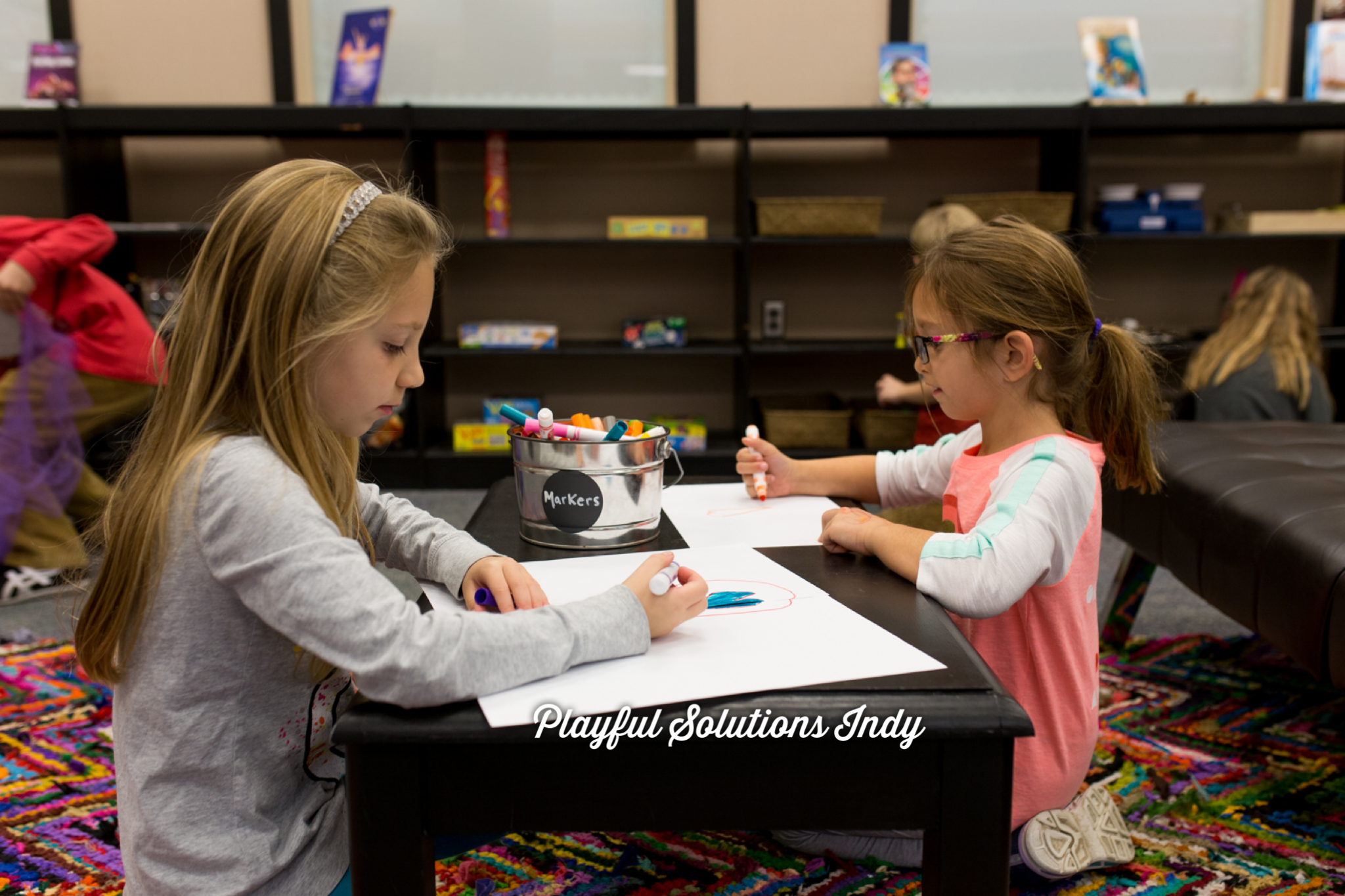 2 girls drawing at a table