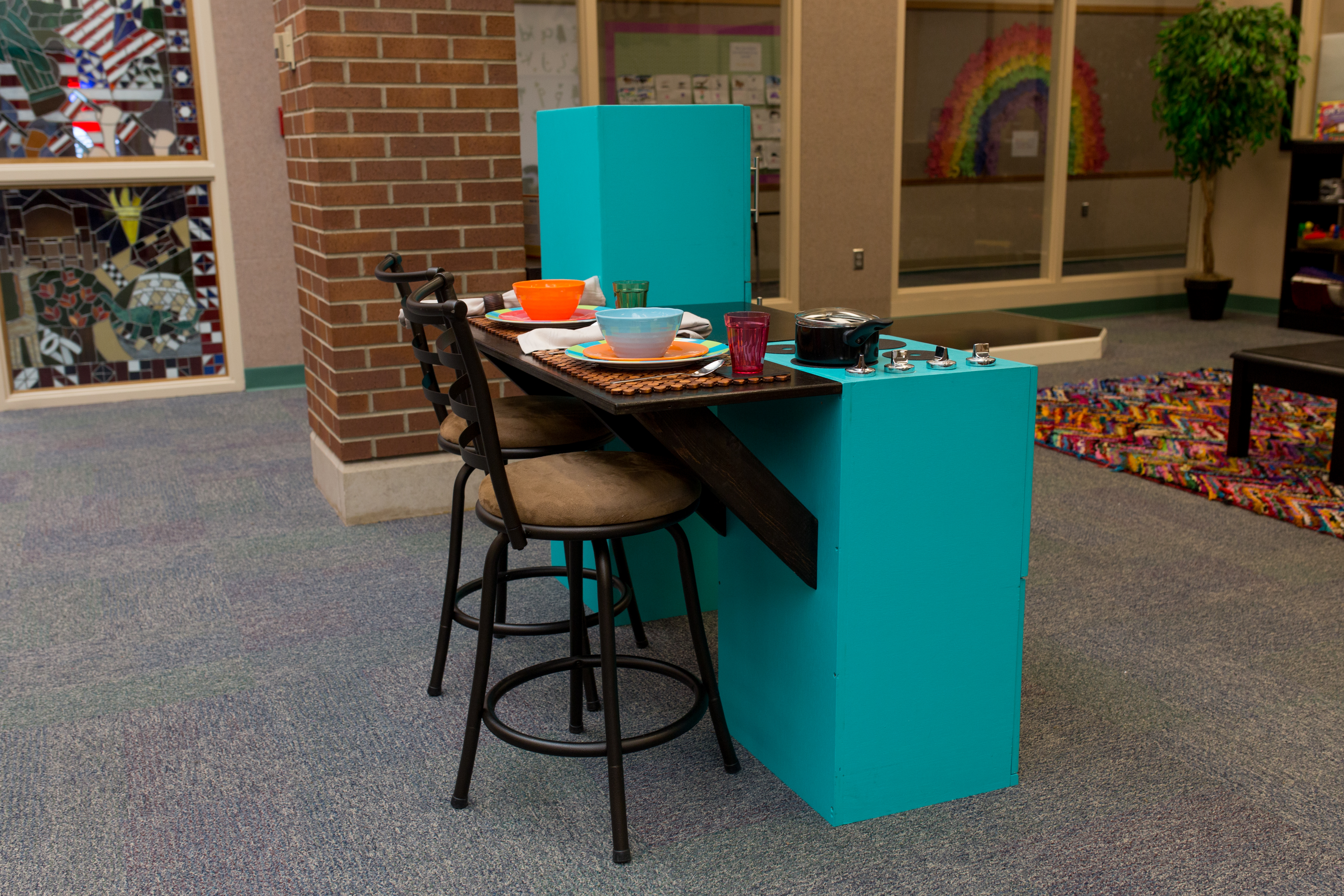 child's kitchen with bar top on the back and stools pulled up to it