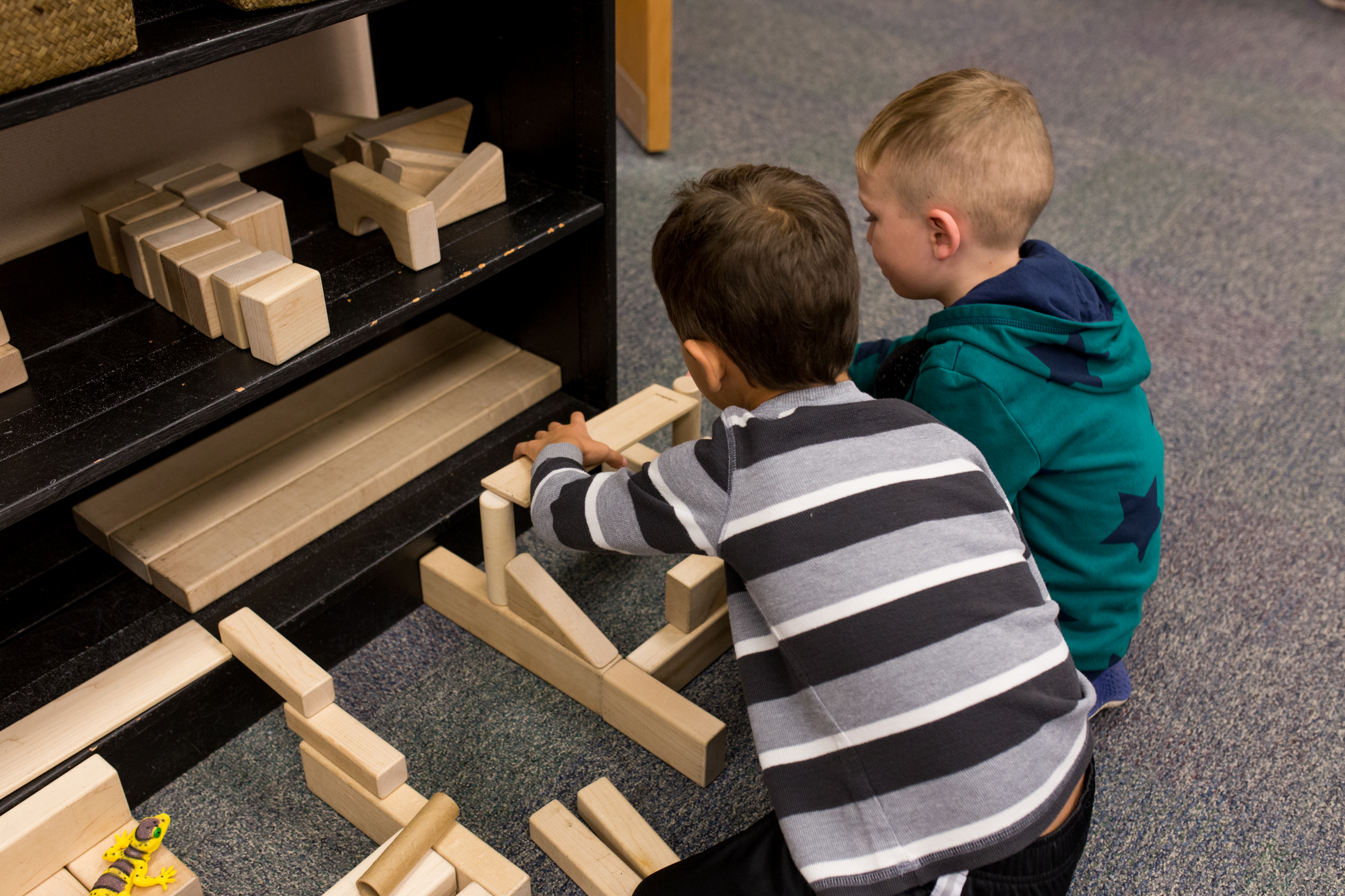 children building with wooden blocks on the floor