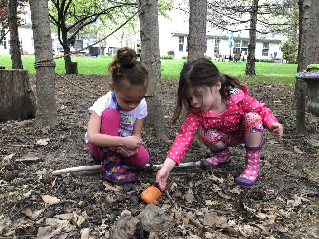 2 young girls investigating an orange on the ground