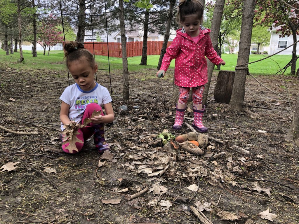 girl holding leaves in her hands to place on the ground