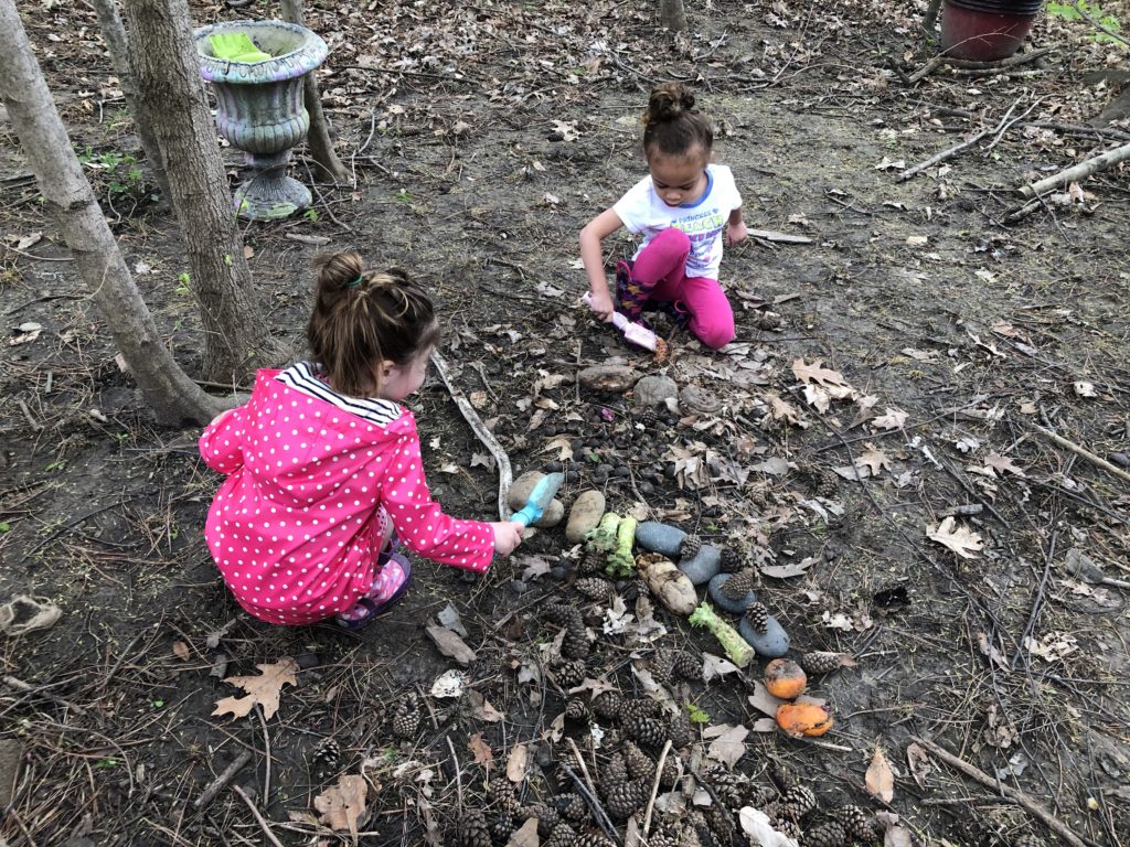 girls arranging fruit on the ground with shovels