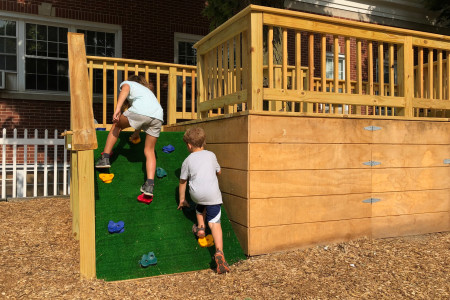 two children scaling a small climbing wall