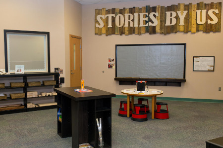 the words Stories By Us mounted on wood slats over a Lego wall