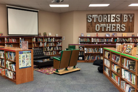 bookcases arranged at alngles under the words Stories by Others mounted on a far wall