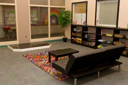 a leather couch on a colorful rug facing a small stage on the floor